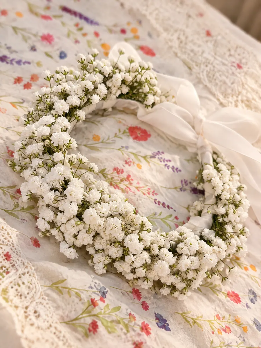 Coroniță de gypsophila albă, pe o față de masă brodată