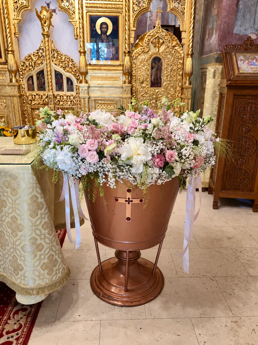 Cristelniță din aramă, decorată cu flori albe și roz, în biserică