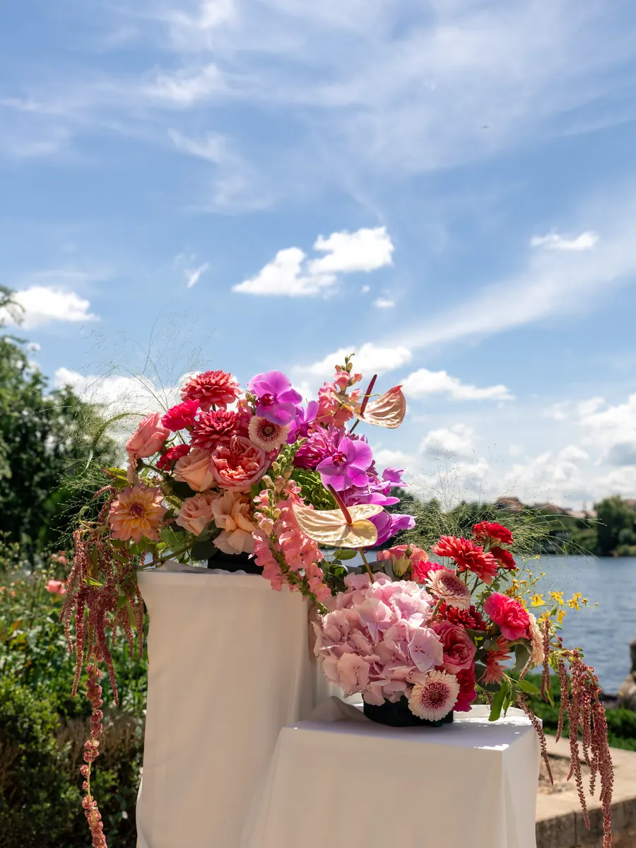Instalație florală roșie și roz pe un piedestal alb, la malul lacului
