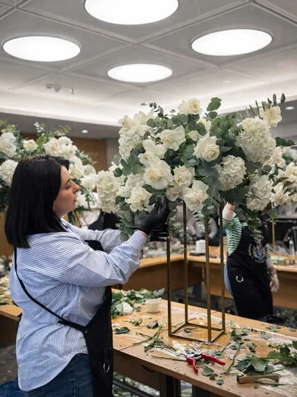 Laura, în atelier, aranjând flori albe pentru un eveniment