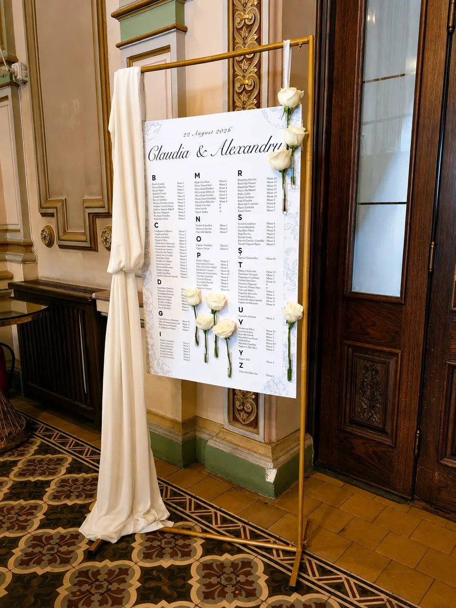 Seating chart pe șevalet auriu, decorat cu trandafiri albi și voal